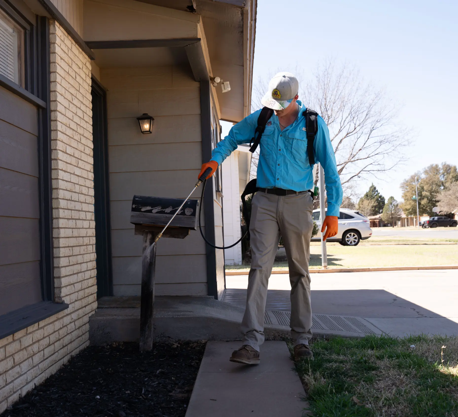 SWAT technician treating the exterior perimeter of a Lubbock home for residential pest control