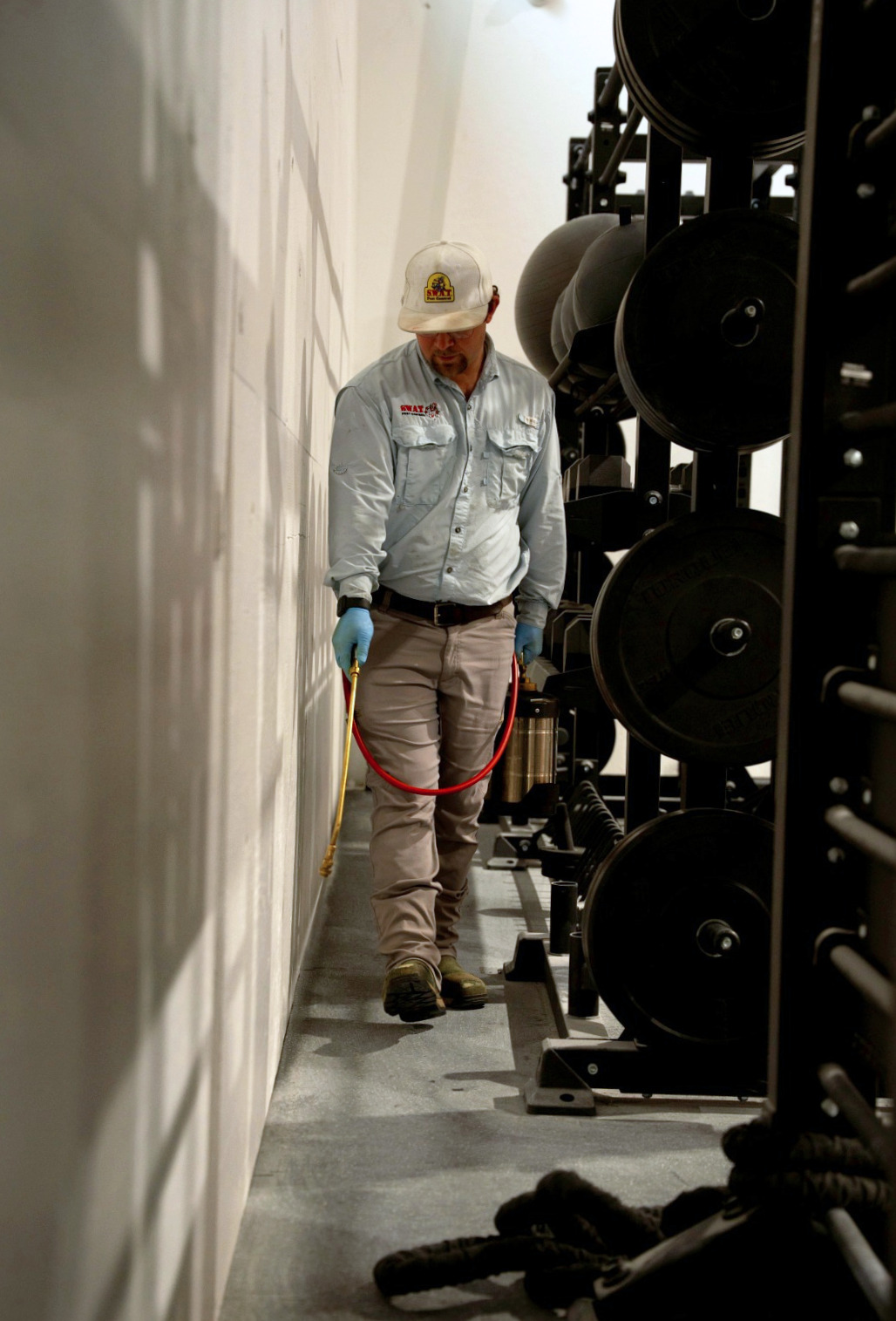 SWAT Pest Control technician performing commercial pest control inside a Lubbock gym facility