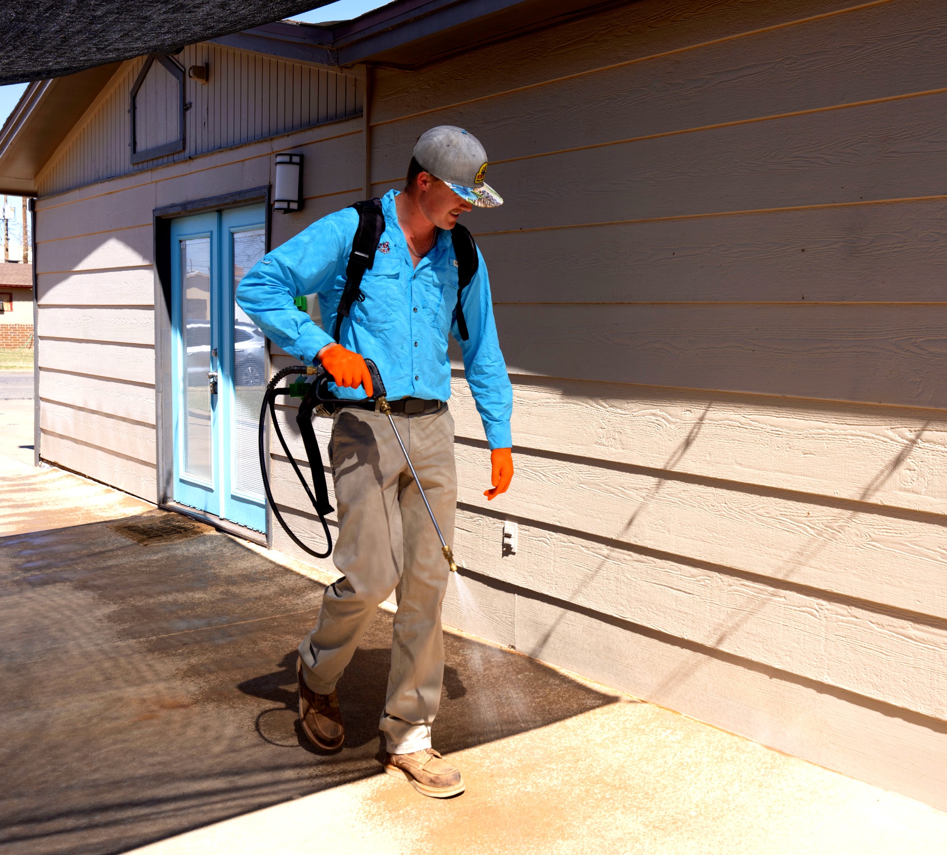 SWAT Pest Control technician applying an exterior perimeter barrier at a Lubbock home
